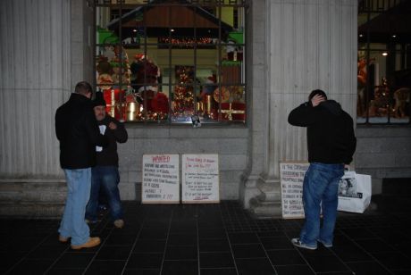 A passing shopper reads the placards.