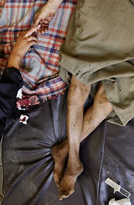 'An injured elderly civilian is comforted inside the besieged Imam Ali shrine'