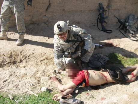 In this image, a different soldier poses with the same corpse.