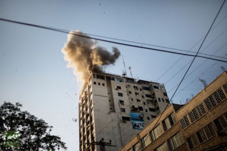Smoke billows as debris flies from the explosion at the local Al-Aqsa TV station in Gaza City on November 18, 2012 after it was attacked during an Israeli airstrike. An Israeli air strike hit a Gaza City media building.(AFP Photo / Marco Longari)
